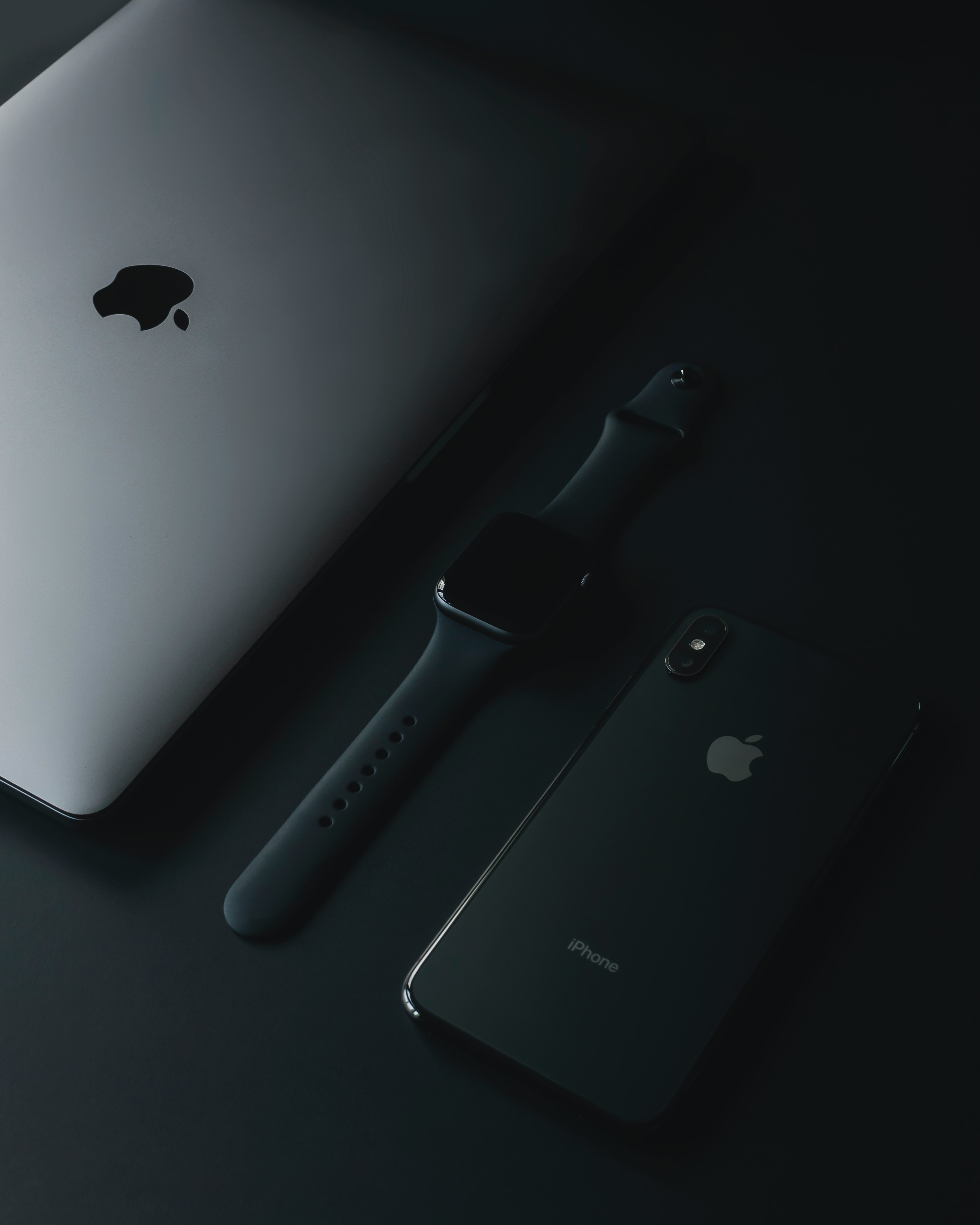 Apple Macbook, Apple Watch, Iphone on a black background.